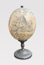 AN EARLY 20TH CENTURY FAUX SCRIMSHAW OSTRICH EGG UPON STAND. (h 22cm)