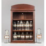 A LATE 19TH/EARLY 20TH CENTURY APOTHECARY BOTTLE COLLECTION WITH GLAZED DISPLAY CABINET. Cabinet (