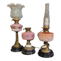 THREE VICTORIAN GILDED BRASS OIL LAMPS One with Corinthian column, opaline glass shade and cranberry