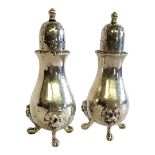 A PAIR OF EARLY 20TH CENTURY SILVER PEPPERETTES Having dome form finials, lion masks, on tripod