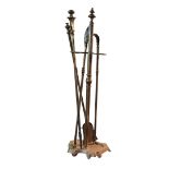 AN EARLY 20TH CENTURY BRASS FIRESIDE COMPANION SET Comprising a pair of tongs, poker shovel and