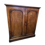 A VICTORIAN MAHOGANY SIDE CABINET With two arched panelled doors enclosing shelves, on plinth