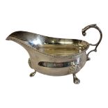 AN EARLY 20TH CENTURY SILVER SAUCE BOAT Having a single handle with shell firm tripod legs,