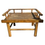 A CHINESE ELM BENCH With woven rattan panel seat, raised on square section legs joined by stretcher.