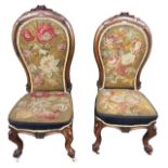 A PAIR OF HIS AND HERS 19TH CENTURY VICTORIAN CARVED WALNUT AND FLORAL UPHOLSTERED NURSING ARMCHAIRS