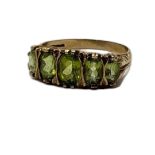 AN EARLY 20TH CENTURY 9CT GOLD AND PERIDOT FIVE STONE RING The oval cut graduated stones in a