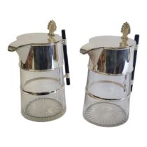 A PAIR OF SILVER PLATED & CLEAR GLASS CHRISTOPHER DRESSER STYLE CLARET JUGS Shell thumb piece on a