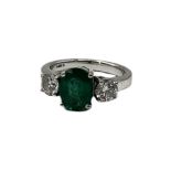 AN 18CT GOLD, EMERALD AND DIAMOND THREE STONE RING The central oval cut emerald, (approx emerald