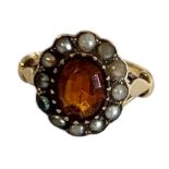 AN EARLY 20TH CENTURY CITRINE AND SEED PEARL RING The central oval cut stone edged with seed petals.