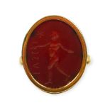 A 19TH CENTURY FRENCH 18CT GOLD AND CARVED GARNET INTAGLIO RING Showing a man taking a stride in