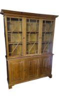 A 19TH CENTURY STYLE PINE TRIPLE BOOKCASE With three astragal glazed doors above panelled cupboards.