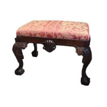 A GEORGE I STYLE MAHOGANY FOOTSTOOL With overstuffed upholstered seat above a shaped shell apron, on