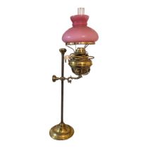 A VICTORIAN BRASS AND GLASS TELESCOPIC OIL LAMP Having a single arm and pink glass shade. (shade