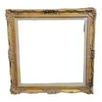 AN EARLY 20TH CENTURY GILDED GESSO PICTURE FRAME Surmounted by scrolling foliage verso, bearing