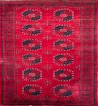 A BOKHARA WOOLLEN RUG Having twelve large red and black elephant foot motifs to red central