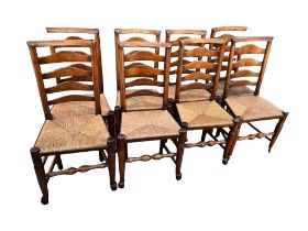 A SET OF EIGHT EARLY 19TH OAK AND ELM LANCASHIRE BILLINGE LADDER BACK DINING CHAIRS With rush seats,