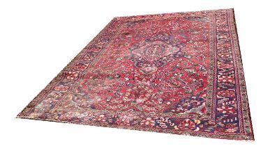 A PERSIAN HIREZ WOOLLEN RUG OF CARPET PROPORTIONS Having blue lozenge to central field on red ground
