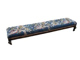 A VICTORIAN LONG JOHN STOOL In tapestry upholstery, on squat cabriole legs. (128cm x 33cm x 20cm)