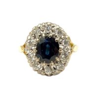 AN 18CT GOLD, SAPPHIRE AND DIAMOND CLUSTER RING The central oval cut sapphire edged with round cut