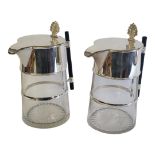 A PAIR OF SILVER PLATED & CLEAR GLASS CHRISTOPHER DRESSER STYLE CLARET JUGS Shell thumb piece on a