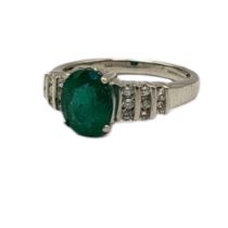 AN 18CT WHITE GOLD, EMERALD AND DIAMOND CLUSTER RING The single oval cut emerald with diamond set