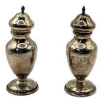 A PAIR OF EARLY 20TH CENTURY SILVER PEPPERETTES Plain baluster form with pierced dome lids,