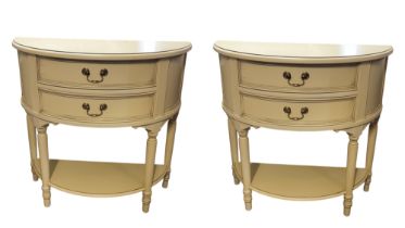 A PAIR OF CREAM DEMILUNE SIDE TABLES With two drawers above lower open shelf. (85cm x 40cm x 80cm)