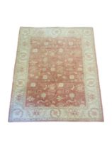 A PERSIAN WOOLLEN RUG Hand woven with floral decoration on amber central field on oatmeal cream