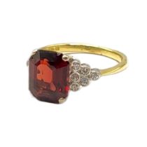 AN 18CT GOLD, GARNET AND DIAMOND RING The rectangular faceted cut stone with diamonds to