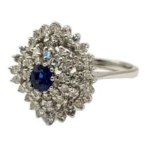 AN 18CT WHITE GOLD, SAPPHIRE AND DIAMOND CLUSTER RING The central round cut sapphire,edged with