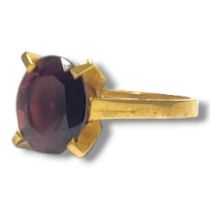 A YELLOW METAL AND GARNET SOLITAIRE RING, YELLOW METAL TESTED AS 18CT YELLOW GOLD Oval cut garnet (