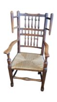 A 19TH CENTURY LANCASHIRE OAK WIING OPEN ARMCHAIR With turned spindles, rush seat turned kegs and