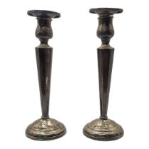 A PAIR OF EARLY 20TH CENTURY STERLING SILVER CANDLESTICKS Having tapering fluted column supports and