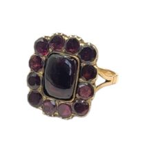 A 19TH CENTURY YELLOW METAL AND GARNET RING The central oval cut garnet with round cut stones to