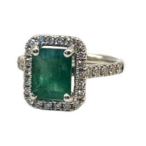 AN 18CT GOLD, EMERALD AND DIAMOND RING The central rectangular faceted emerald edged with