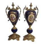 A PAIR OF CONTINENTAL POTTERY AND GILT BRASS URNS Twin brass handles and mounts,decorated with