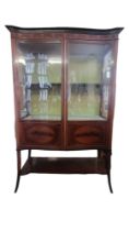 AN EDWARDIAN MAHOGANY AND MARQUETRY INLAID DISPLAY CABINET With two serpentine glazed and oval