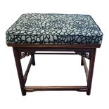 A CHINESE HARDWOOD STOOL With upholstered seat above a carved and pierced apron, on turned legs. (
