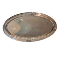 AN ARTS AND CRAFTS SILVER PLATE ON COPPER OVAL MIRROR With applied florets, shaped border and