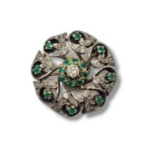 A VINTAGE YELLOW METAL AND GEM SET BROOCH The central round cut diamond,edged with green stones on a