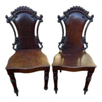 A PAIR VICTORIAN SOLID MAHOGANY HALL CHAIRS With carved and pierced backs solid seats, on turned