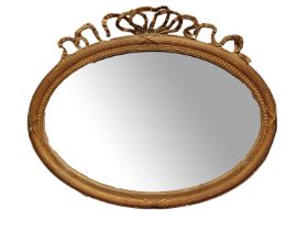 A GEORGIAN GILT FRAME OVAL MIRROR Having classical ribbon finial, carved gesso decoration and