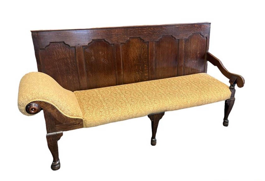 AN 18TH CENTURY DESIGN OAK SETTLE With panelled back above open arm and scroll end, upholstered in a