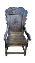 A 17TH CENTURY OAK WAINSCOT CHAIR With organic carved crest and lozenge panel back, shaped scroll