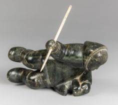 AN EARLY 20TH CENTURY INUIT SOAPSTONE CARVING OF A HUNTER WITH BONE SPEAR.