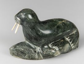 AN EARLY 20TH CENTURY INUIT SOAPSTONE CARVING OF A WALRUS WITH BONE TUSKS.
