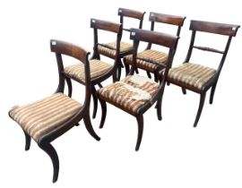 A SET OF SIX REGENCY CARVED MAHOGANY BAR BACK DINING CHAIRS With drop in seat, raised on saber legs.