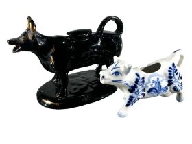 A VICTORIAN JACKFIELD BLACK AND GOLD COW CREAMER. TOGETHER WITH DELFT BLUE AND WHITE COW CREAMER. (