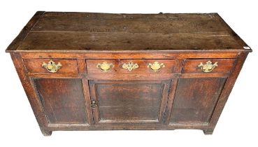 AN 18TH CENTURY OAK DRESSER BASE With three drawers above central cupboard door, raised on block