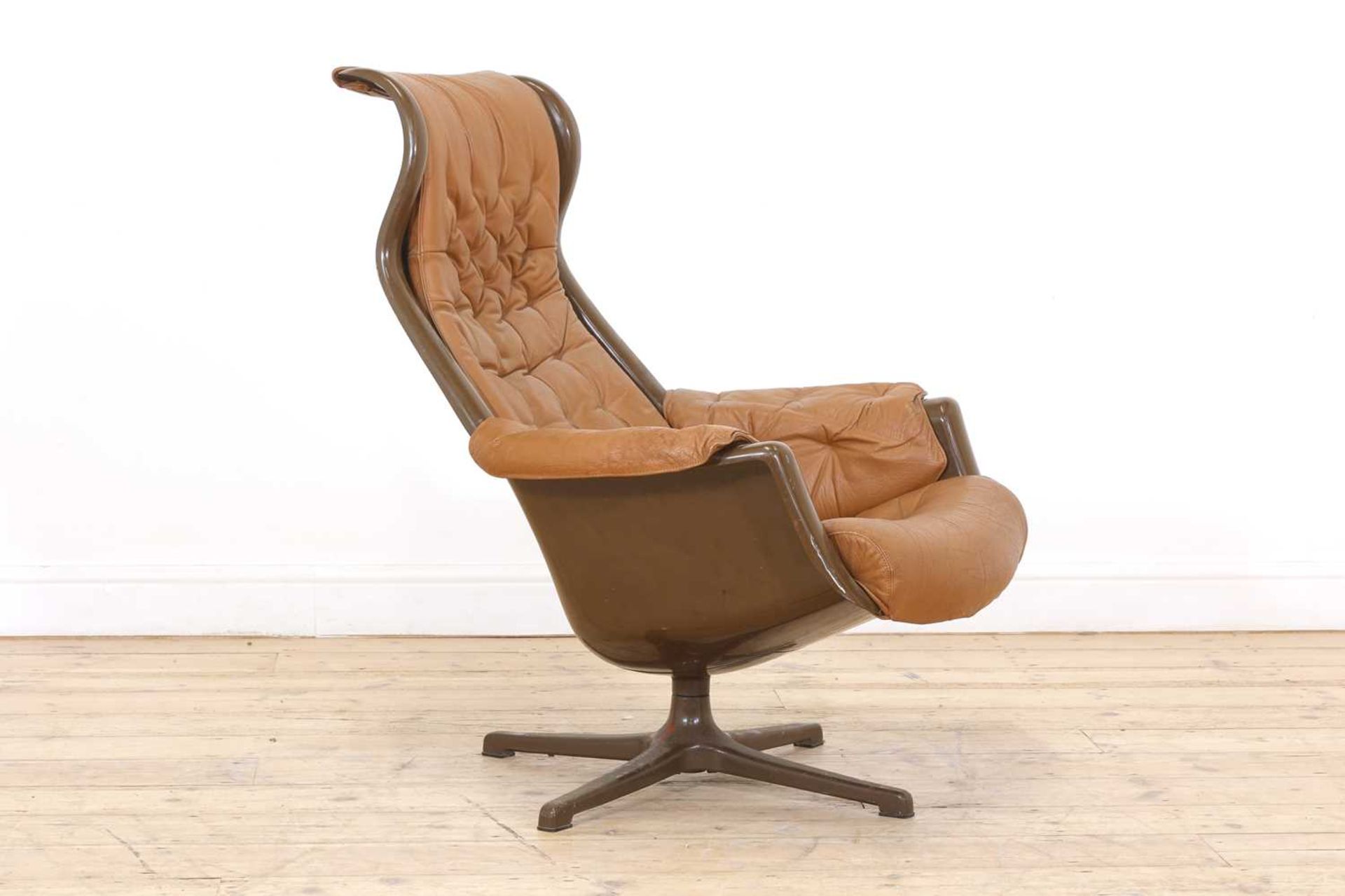 A Danish brown moulded plastic and tan leather lounger,